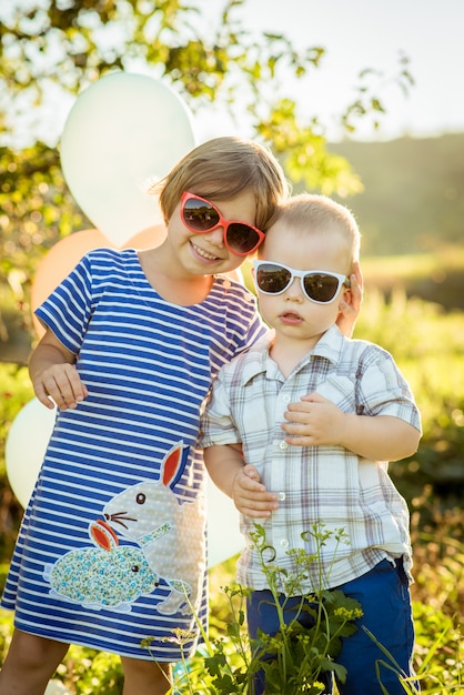 Мальчик и девочка в очках обнимаются на природе