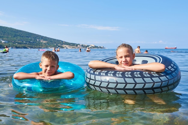 男の子と女の子がおもちゃの救命浮き輪で泳いでいます