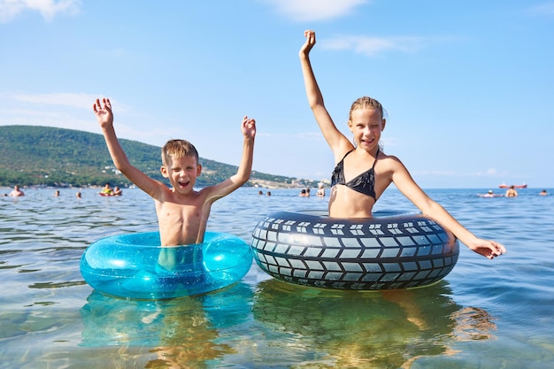 Boy and girl swimming with toy lifebuoys