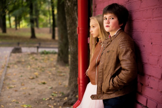 Boy and girl teenagers posing against a brick wall background