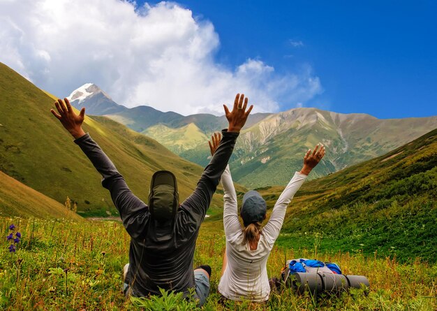 Foto ragazzo e ragazza di turisti si rilassa su un prato verde con vista sulle montagne