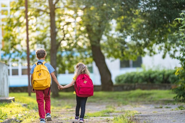 Photo boy and a girl with backpacks are walking down the street