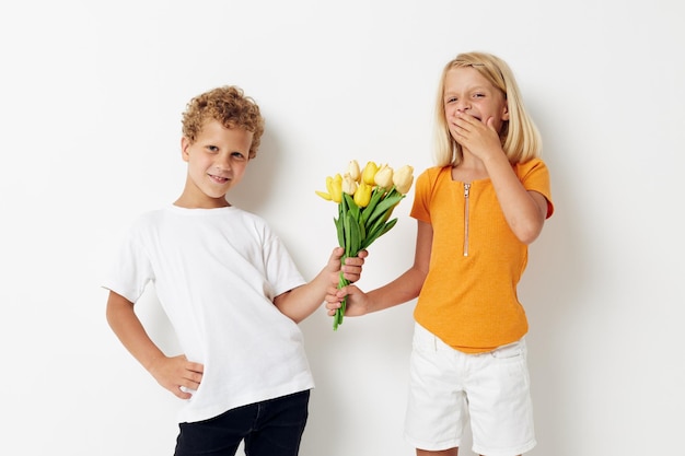 Мальчик и девочка с букетом цветов подарок на день рождения праздник детства светлый фон