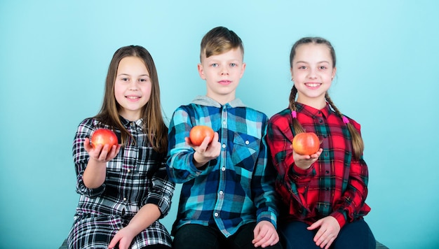 Photo boy and girls friends in similar checkered clothes eat apple teens with healthy snack healthy dieting and vitamin nutrition eat fruit and be healthy group teenagers hold apples healthy lifestyle