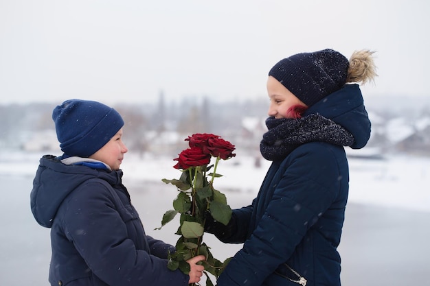 男の子は女の子にバラの花束を与えます。聖バレンタインデーのコンセプト