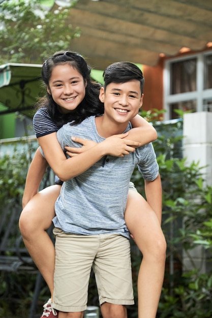 Boy Giving Piggyback Ride to Twin Sister