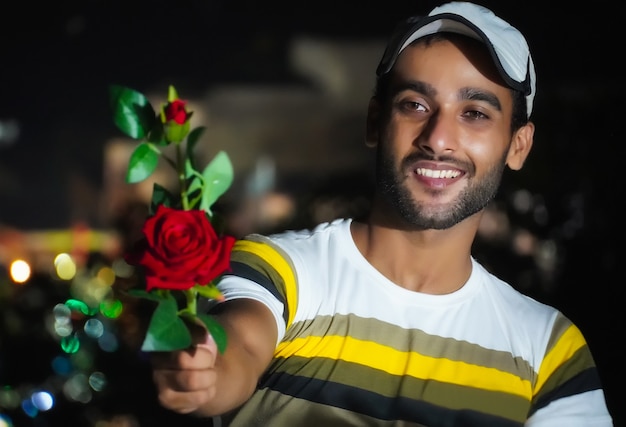 Boy giving rose to his lover - red rose in hand