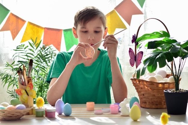 A boy in a green Tshirt paints eggs Preparation for Easter