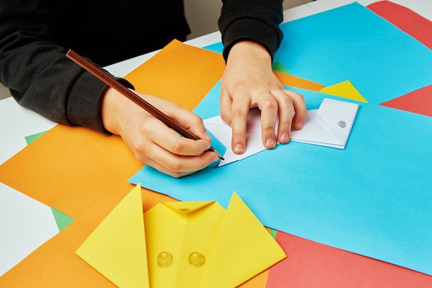 Boy hands making origami dog with colorful paper sheets Child creative education