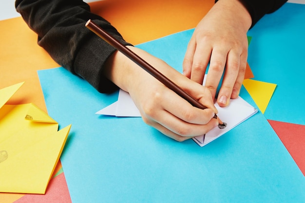 Mani del ragazzo che fanno cane origami con fogli di carta colorati, educazione creativa del bambino