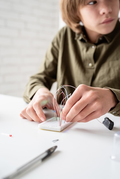 Mani del ragazzo che lavorano con luci a led sulla scheda sperimentale per progetto scientifico