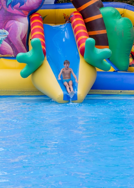 Boy has into pool after going down water slide during summer little boy sliding down water slide and having fun