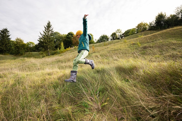 Boy having fun run and jump outdoor near forest