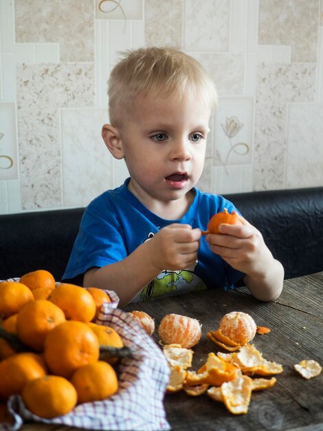 家のソファに座ってオレンジを食べている少年