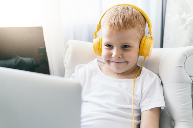 A boy in headphones looks at a laptop screen