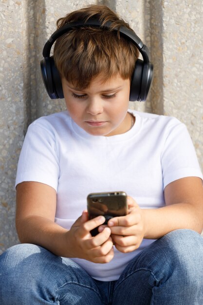 Boy in headphones with smartphone listening to music in the park