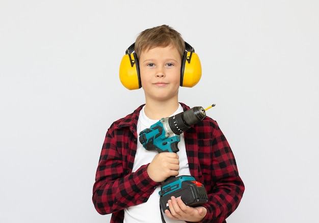 Мальчик в шлеме играет в строителя с инструментами. Изолированные