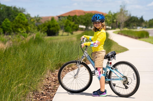 ヘルメットをかぶった少年が自転車に乗って 安全ヘルメットをかぶった少年が都市公園で自転車に乗って 子供最初の自転車 子供屋外