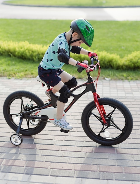 Мальчик в шлеме с велосипедом на открытом воздухе