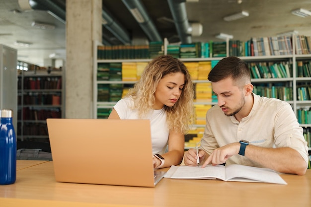 Boy help his girlfriend preparing for exam in public library Education concept