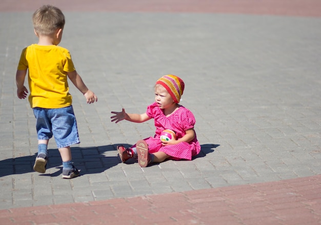 Boy helping sitting girl to stand up