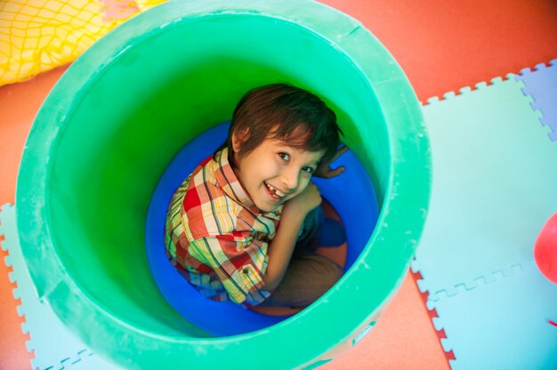 プラスチック製の樽に隠れている少年