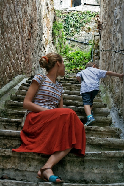 A boy and his mother are walking in the old town Child climbs the stairs in the old town of kotor