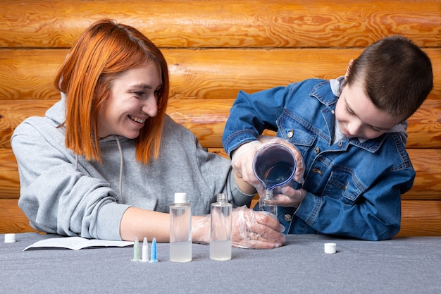 Ragazzo e sua madre, gli scienziati versano acqua in una bottiglia con elementi chimici, per esperimenti a casa