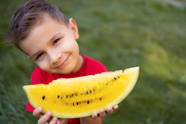 A boy hold in hands yellow watermelon.