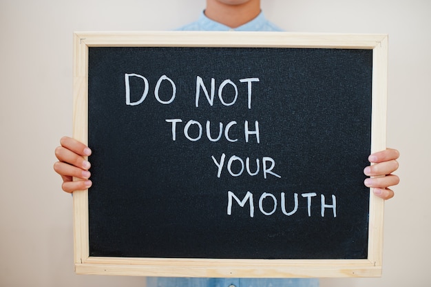 Boy hold inscription on the board with the text do not touch your mouth