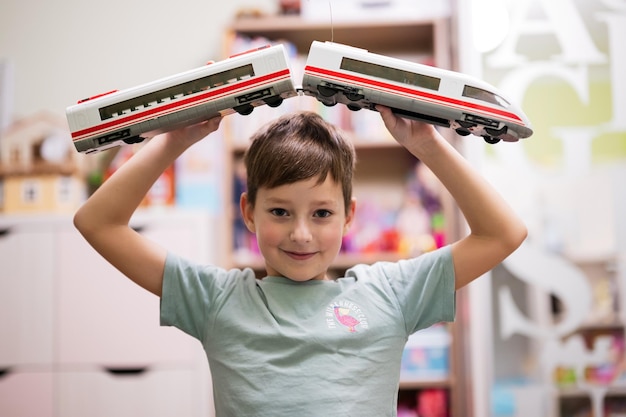 Photo boy hold toy high speed train in hands at children's room
