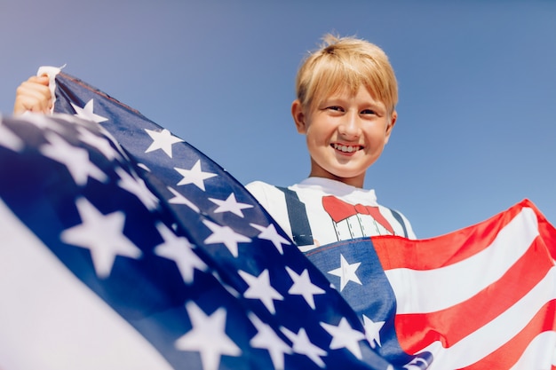Мальчик держит американский флаг. патриоты америки.