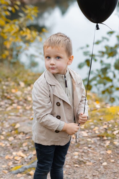 Photo a boy holding a balloon near the lake