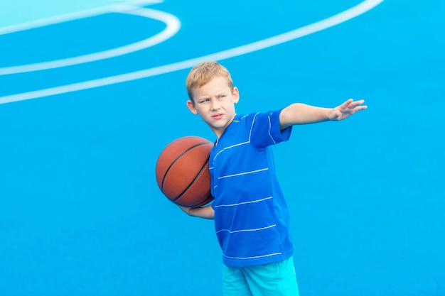 Boy holding basketball while standing on sports court