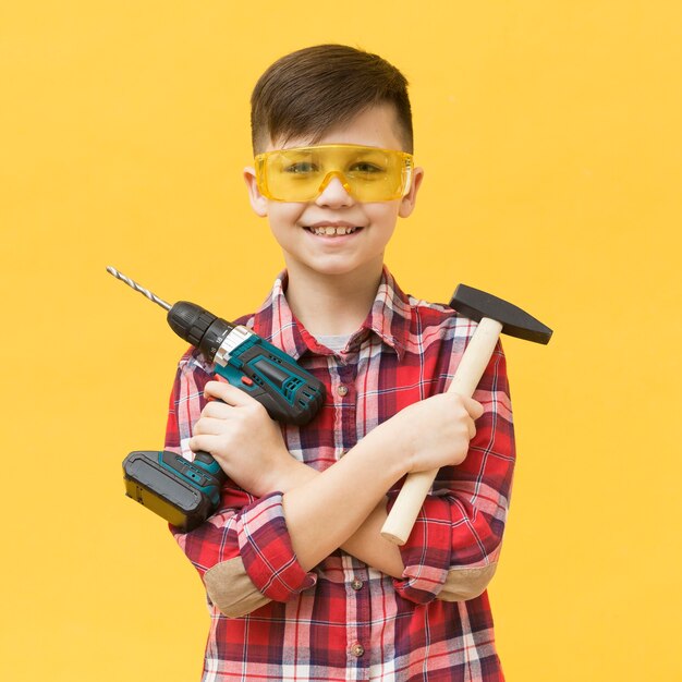 Boy holding drilling machine and hammer