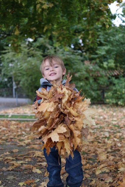 Boy holding dry leaves in park
