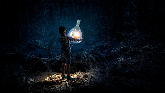 Boy holding flask with illuminated landscape in it. Mixed media