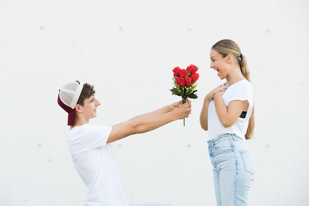 Boy holding flowers making proposal at girlfriend