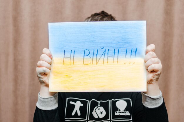 boy holding a picture with the words no war