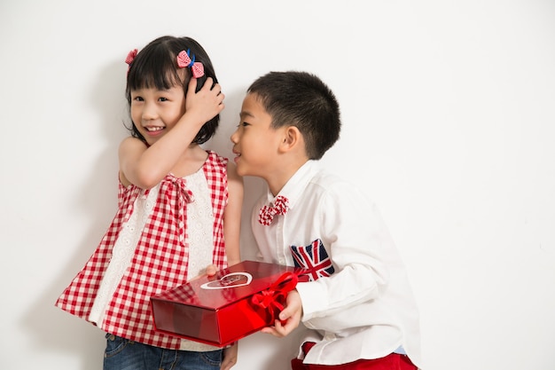 A boy holding present for give a gift to a girl with white background.