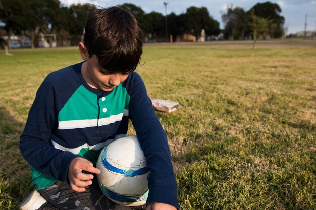 Foto ragazzo con una palla da calcio sull'erba