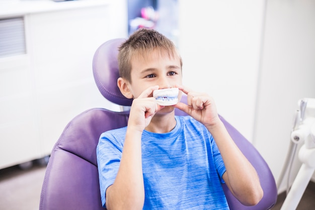 Photo boy holding teeth plaster mold in front of his mouth