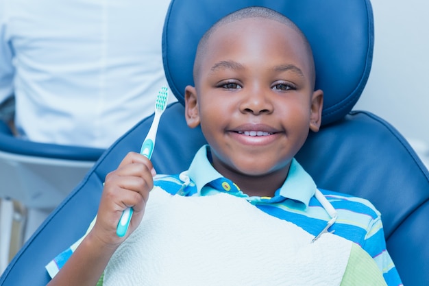 歯科医の椅子に歯ブラシを持っている少年