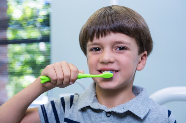 診療所の椅子に座って歯ブラシを持っている少年