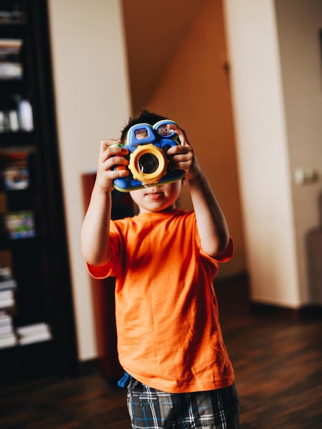 Boy holding toy camera at home