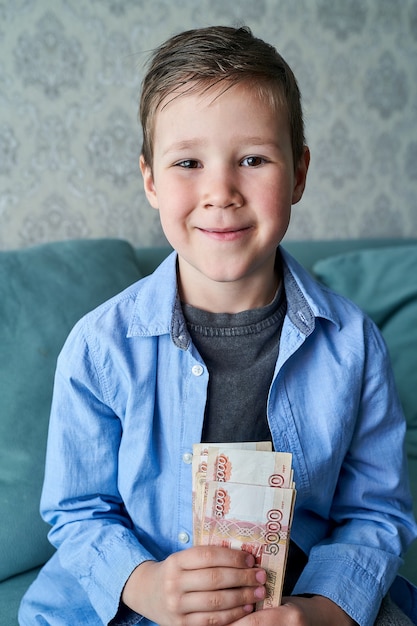 Boy holds a bundle of Russian five thousand dollar bills in his hands.