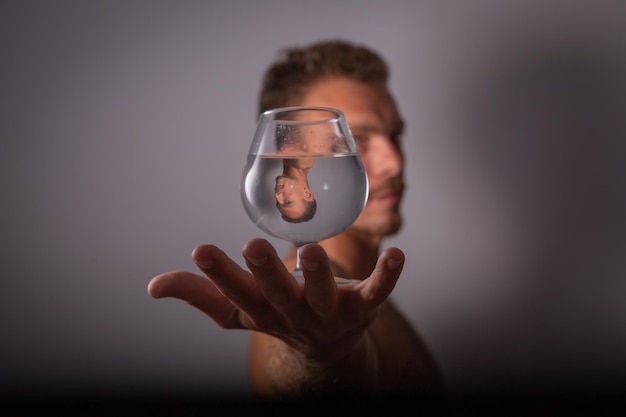 A boy holds a glass of water with his reflection Distorted perspective Abstraction Creative and artistic man