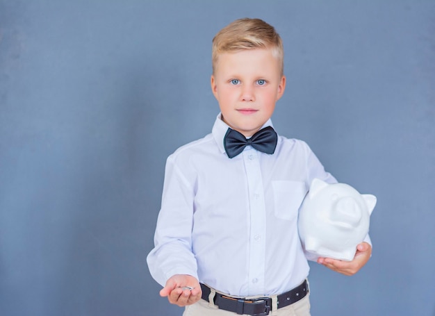 The boy holds in his hands a piggy bank bank and coins saving money