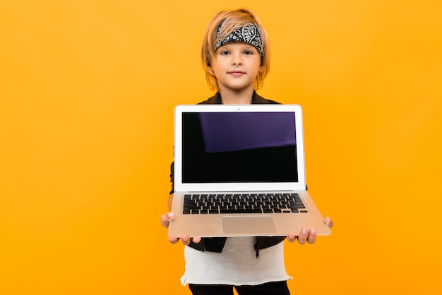 Photo boy holds a laptop with the on yellow