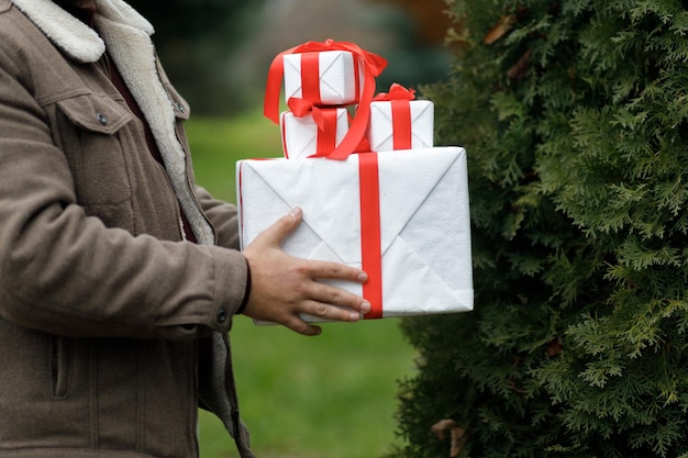 A boy holds a New Year's gifts in his hands Beautiful gifts New Year's decor Christmas tree Preparation for the holiday